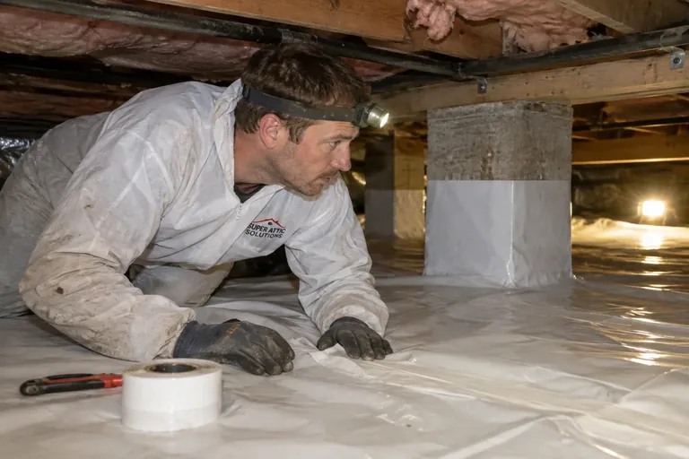 Crawl space with new vapor barrier and a technician at work